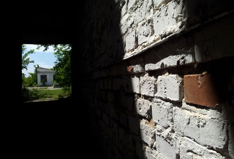 Світло на цегляній стіні та будиночок у проході в стіні ангару. Харків, Україна