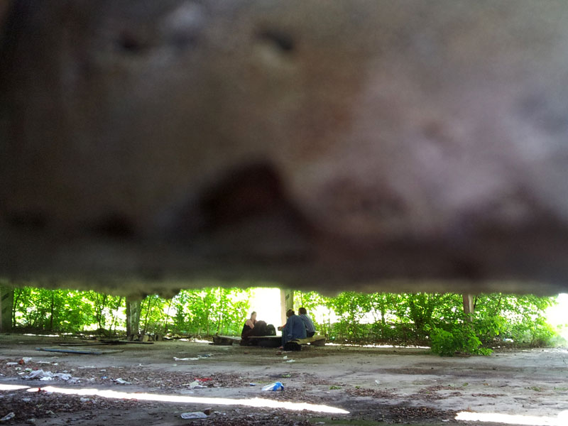 Люди за столиком в покинутому ангарі. Воєнвєд. Харків, Україна