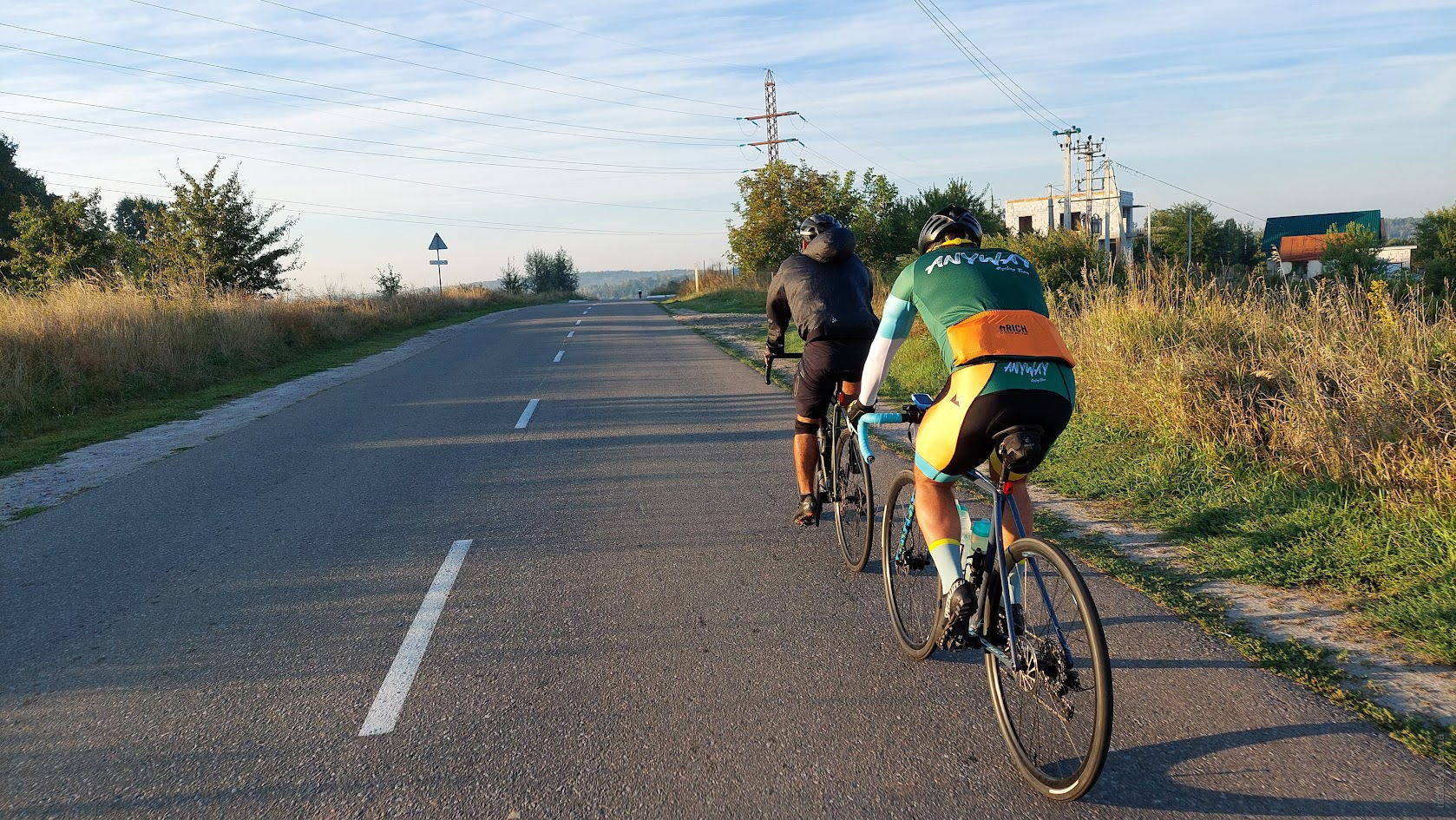 Два велосипедисти. В чорному одязі та в командній формі Anyway Cycling