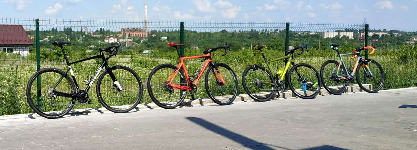 Чотири гревел-байки біля забору. Specialized Diverge E5 Elite 2019, Giant TCX, Cannondale Slate, Giant TCX.