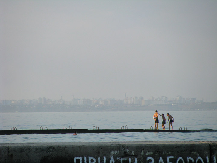 Вечернее море на пляже «Дельфин» в Одессе. Ныряльщики на пирсе. На фоне — дома Крыжановки, Лесков или Фонтанки