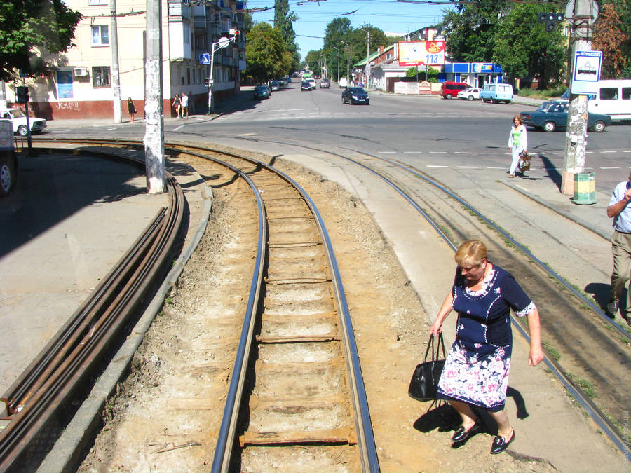Ремонт покрытия возле трамвайной колей. Женщина перелезает через рельсы. Житомир